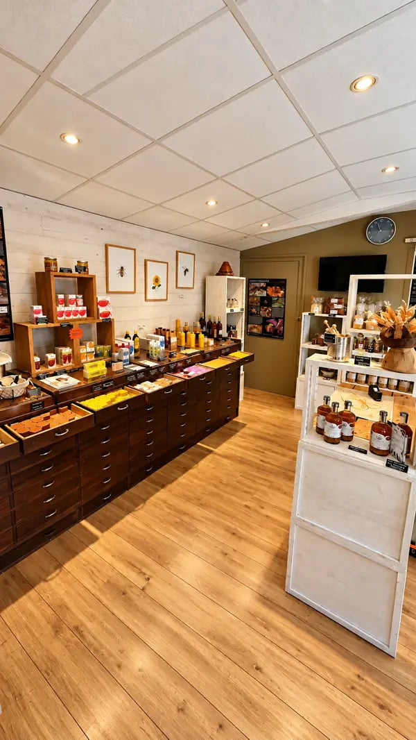 Intérieur du magasin : parquet, meuble à tiroirs, miels, bougies et savons